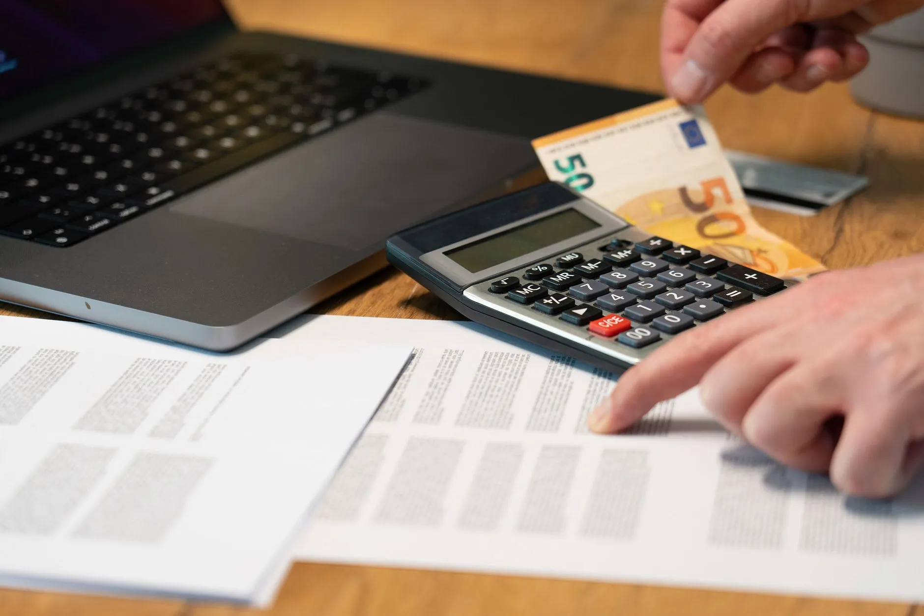 A calculator next to a stack of Euro banknotes and coins, representing property costs in Spain