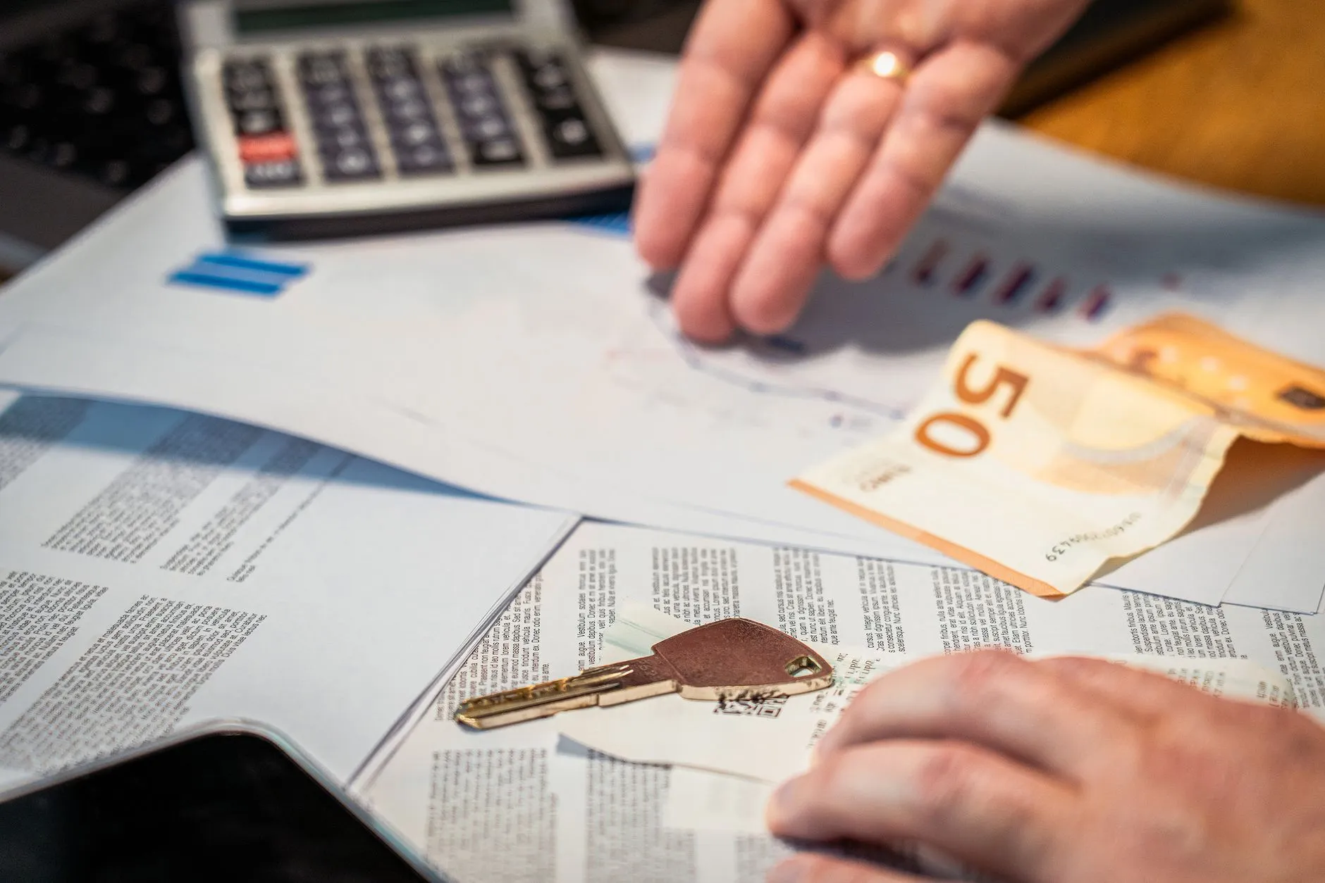 Calculator showing costs, with Euro banknotes and legal papers on a desk, representing conveyancing fees.